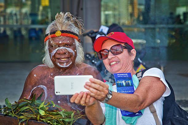 Sydney,Australia - April 12,2015: A woman takes a selfie with aboriginal elder Uncle Max Eulo as he performs a traditional smoking ceremony at an urban regeneration event in White Bay.