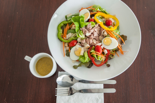 Tuna and vegetable salad on wooden table with pumpkin dressing