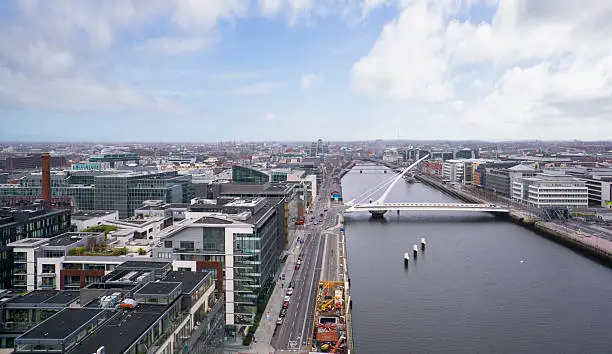 Aerial shot from a drone of the Dublin Docklands, looking West, with a spectacular view of the river Liffey from beyond the Samuel Beckett Bridge. The Ulster Bank building, The Dublin Spire and Liberty hall are all visible on the Horizon