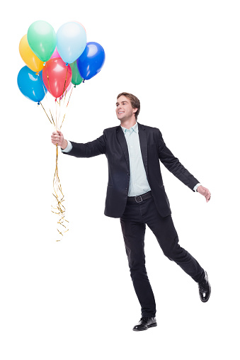Photo of young smiling handsome man. Man holding a lot of colourful balloons and standing on white background. Concept for happy birthday