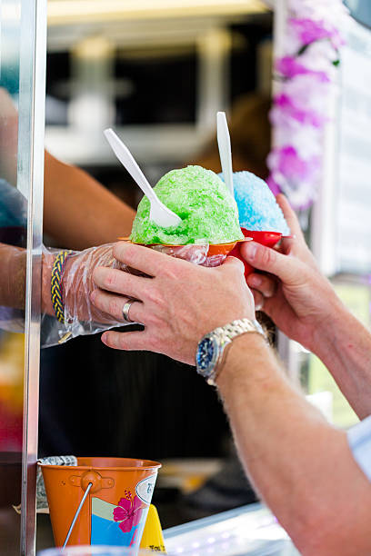 Man getting two snow cones from vendor at barbecue festival