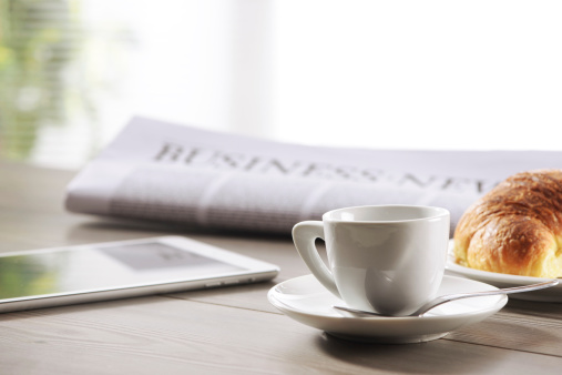 Morning coffee and croissant on newspaper