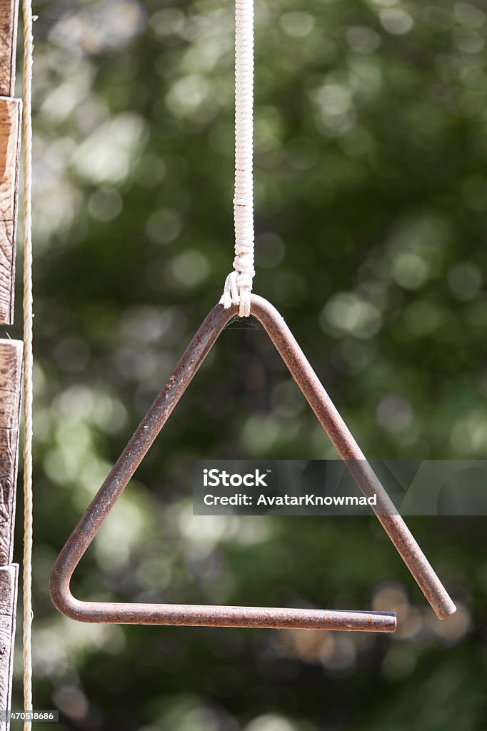 Dinner Bell A vertical image shows a close up of a musical triangle on a farm. Selective focus on the triangle, which hangs from a white rope. Dinner Bell Stock Photo