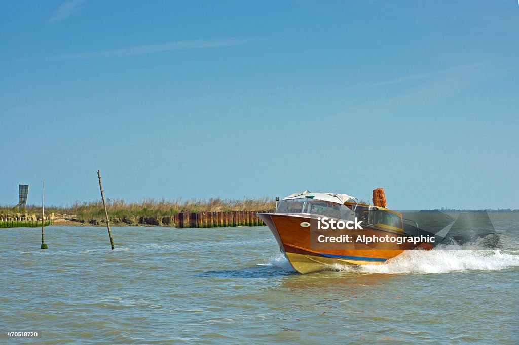 Alilaguna water taxi Water taxi going to Venice airport. This is one of the wooden hulled 50s style taxis and is seen on its way through the allotted route marked by wooden stakes either side. Retro Style Stock Photo