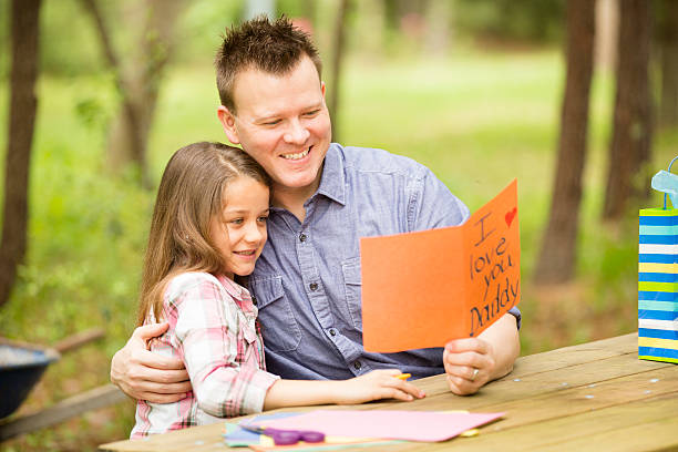 tata córka pokazuje ręcznie robiony dzień ojca karty.   na zewnątrz.   dziecko rodzic. - fathers day greeting card father child zdjęcia i obrazy z banku zdjęć