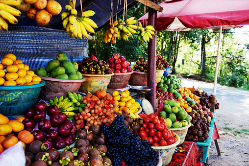 Piles and bunches of fresh fruits: banana,apple,mandarine,mangosteen,passion fruit,red grapes,mango and tomato.