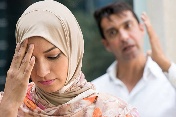 Frustrated woman and man in argument serious muslim woman and a very upset man in the background, they're arguing iranian culture stock pictures, royalty-free photos & images