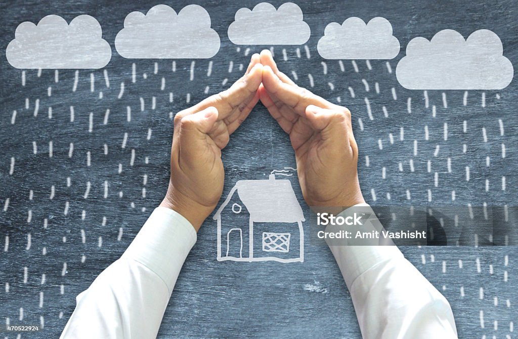 Hands Protecting House Hands Protecting House from Bad weather on chalkboard. Storm Stock Photo