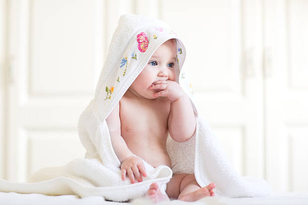 adorable baby mädchen sitzen unter handtuch nach bad - baby blanket fotos stock-fotos und bilder