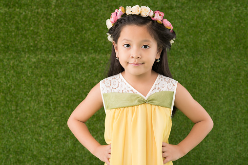 Confident little girl wearing floral wreath of roses