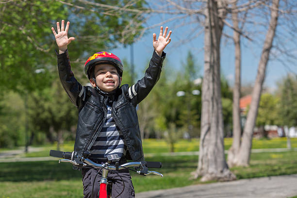 Riding bike Happy young boy riding his bike hands up. long sleeved recreational pursuit horizontal looking at camera stock pictures, royalty-free photos & images