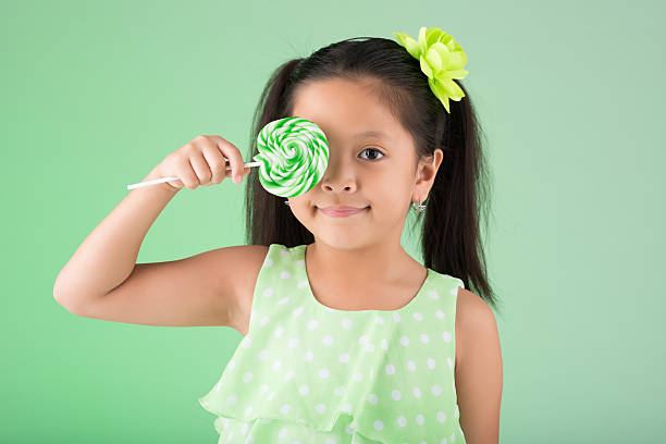Little Filipino girl covering her eye with sugarplum