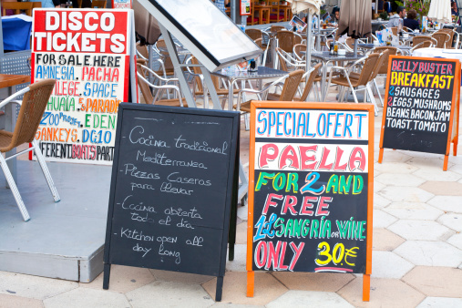 Ibiza, Spain - June 24, 2013: club ticket selling board and tabloids with menu in a terrace at a beach restaurant