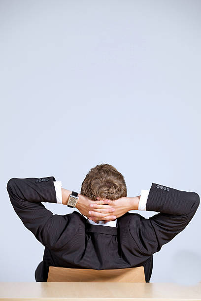 istock businessman sitting in office with hands behind head 470546304
