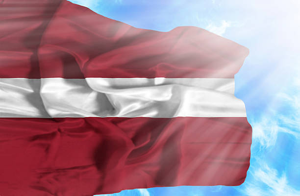 istock Latvia waving flag against blue sky with sunrays 470547225