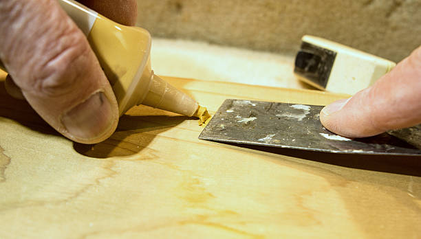 DIY- repairing a hole in a wood board with putty and putty knife.  From the view and perspective of the person doing this project.