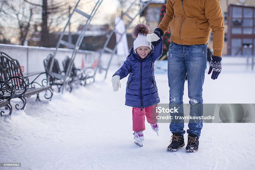 Adorabile bambina con giovane papà sulla pista di pattinaggio - Foto stock royalty-free di Adulto