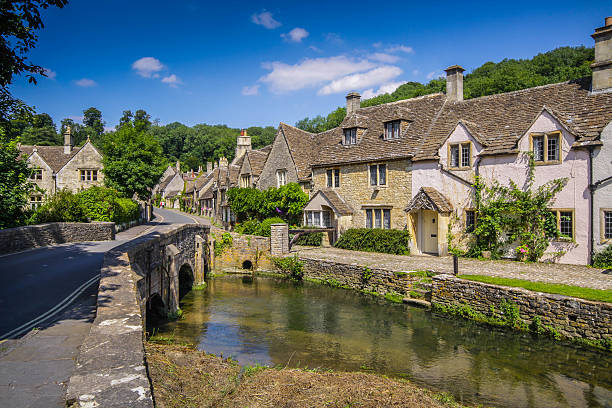 Castle Combe, Wiltshire, UK. A view along he village main street from the bridge with river in the foreground. wiltshire stock pictures, royalty-free photos & images