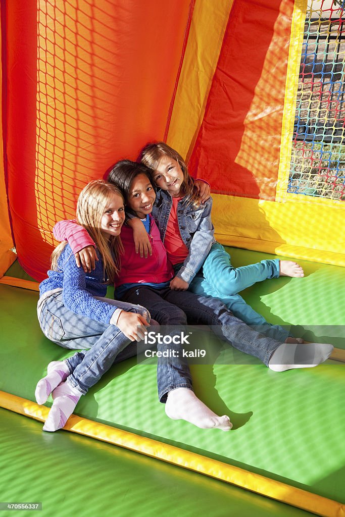 Children in bounce house Multi-ethnic girls (ages 8 to 10 years) playng in inflatable bouncy castle. Bouncy Castle Stock Photo