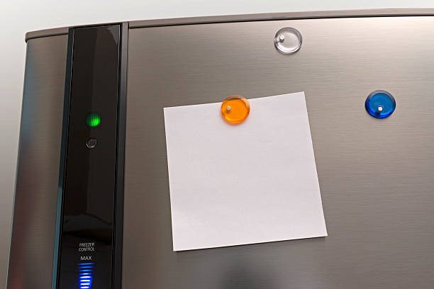 Note on a fridge. Coloured magnets holding a note on a refrigerator. The note is left blank for buyer's own text. magnet photos stock pictures, royalty-free photos & images