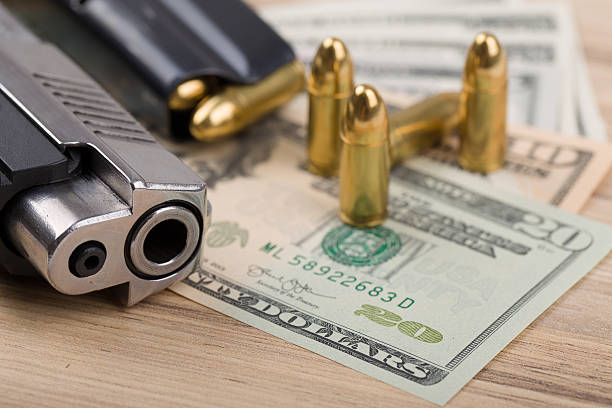 arme à feu avec des balles sur les billets en dollars us - currency crime gun conflict photos et images de collection
