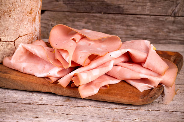 Fresh Mortadella Slices Slices of fresh mortadella and bread on wooden board. emilia romagna photos stock pictures, royalty-free photos & images