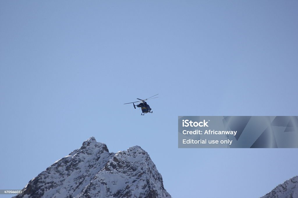 Blue helicopter in the clear sky Kühtai, Austria - February 6, 2014: In winter Kühtai is Austria´s highest winter sport village (2020m) and famous for perfect skiing and snowboarding conditions. The Alpine Mountains of Kühtai are a well known alpine excursion destination in Tyrol, Austria. People enjoy their winter holidays  with skiing on a perfect white ski piste. In the Alpine region sport accidents happen and helicopter transport the injured people to the next hospital. Accidents and Disasters Stock Photo