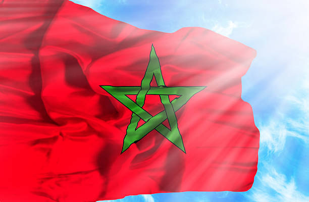 istock Marocco waving flag against blue sky with sunrays 470566951