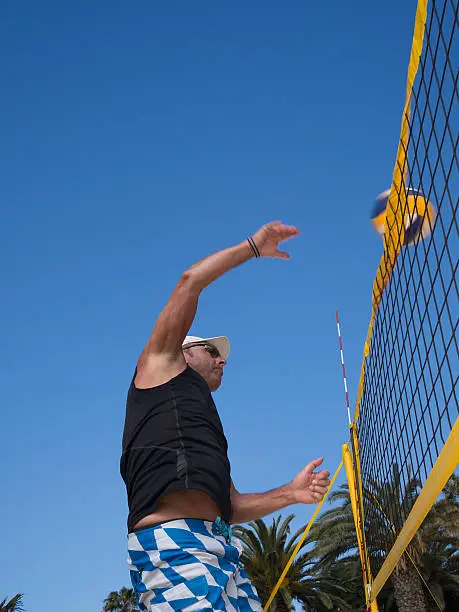 Man hits the volleyball over the net