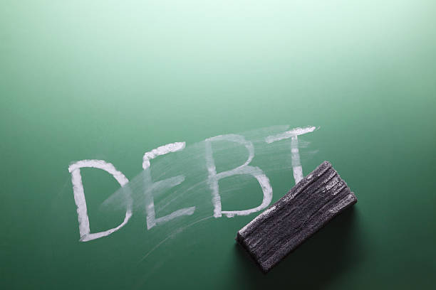 Erasing Debt The word debt partially erased on a chalkboard. board eraser stock pictures, royalty-free photos & images