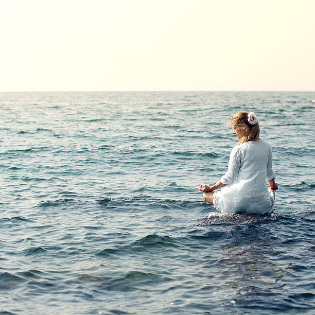istock Woman meditating at the sea 470578684