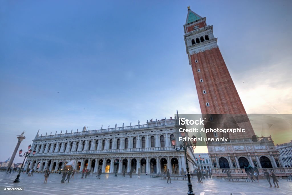 Bell Tower San Marco Venice Venice, Italy - April 10, 2015: This is a wide angle image of the Bell Tower in San Marco Square in Venice, Italy at dusk with golden light on the right of the frame. There are tourist in the square taking photographs and talking The image is a combination of 3 bracketed images combined in HDR software. 2015 Stock Photo