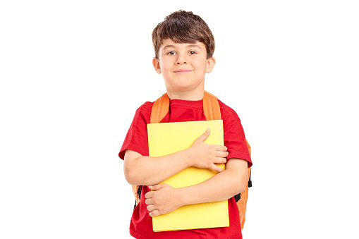 Smiling cute schoolboy with backpack holding books and looking at camera isolated on white background