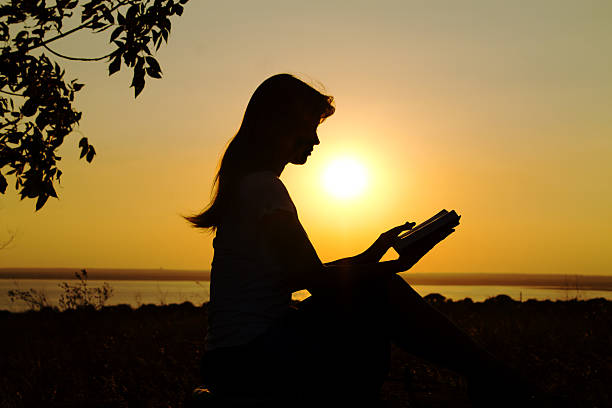 istock silhouette of a girl reading at sunset 470599879