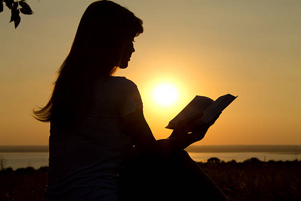 istock silhouette of a girl reading at sunset 470602111