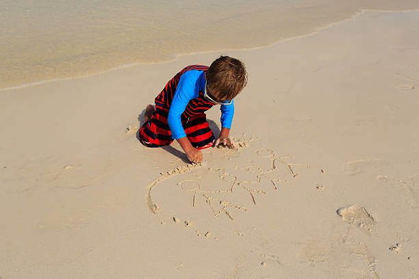 istock little boy drawing family on the beach 470603224