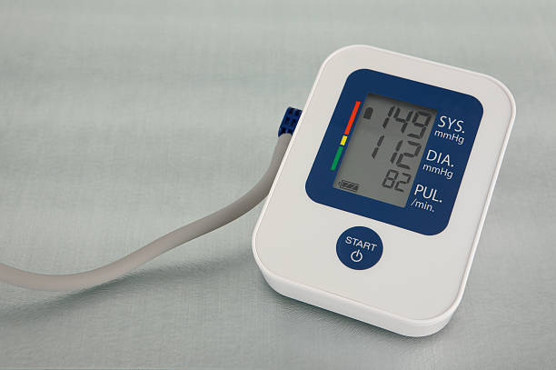 A blood pressure monitor displaying high readings on the digital display. The monitor is showing both the systolic pressure and the diastolic pressure together with the pulse rate. To the left of the screen is a traffic light indicator corresponding to the world health organisation classification displaying a severe hypertension reading.