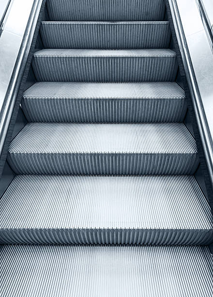 istock Shining metal escalator moving up, vertical monochrome photo 470603948
