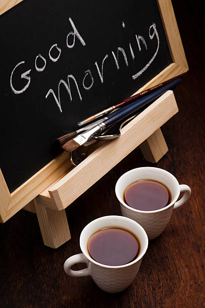 Good Morning chalk writing. Cups of tea and brushes stock photo