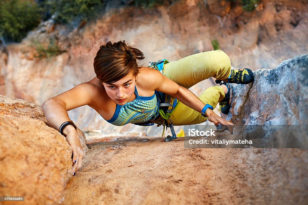 Rock climber climbing up a cliff female rock climber climbs on a rocky wall 2015 Stock Photo