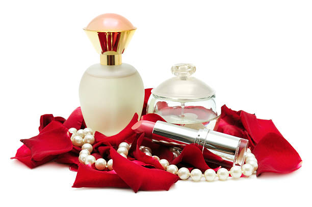 Perfume and pearl necklace in rose petals. Isolated.