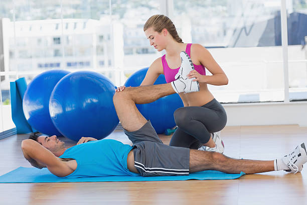 istock Female trainer helping man with his exercises at gym 470617852