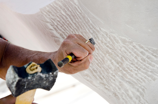 Sculptor carving marble with his tools of yellow