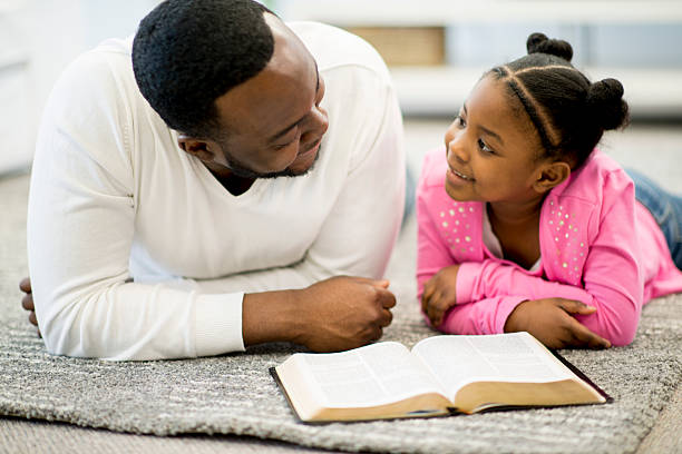 pai e filha estudar a bíblia - family reading african descent book imagens e fotografias de stock