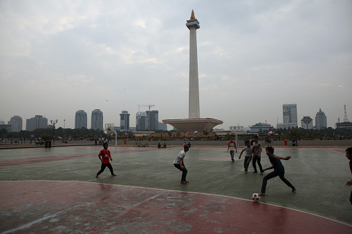 Jakarta, Indonesia - August 17, 2011: Children play football at the foot of the National Monument or the Monas in Jakarta, Central Java, Indonesia.