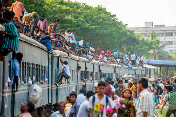 Passengers on the roof of train, Dhaka, Bangladesh Dhaka, Bangladesh - October 5, 2014: Passengers are standing or sitting on the roof of train in a small railway station in Dhaka india train stock pictures, royalty-free photos & images