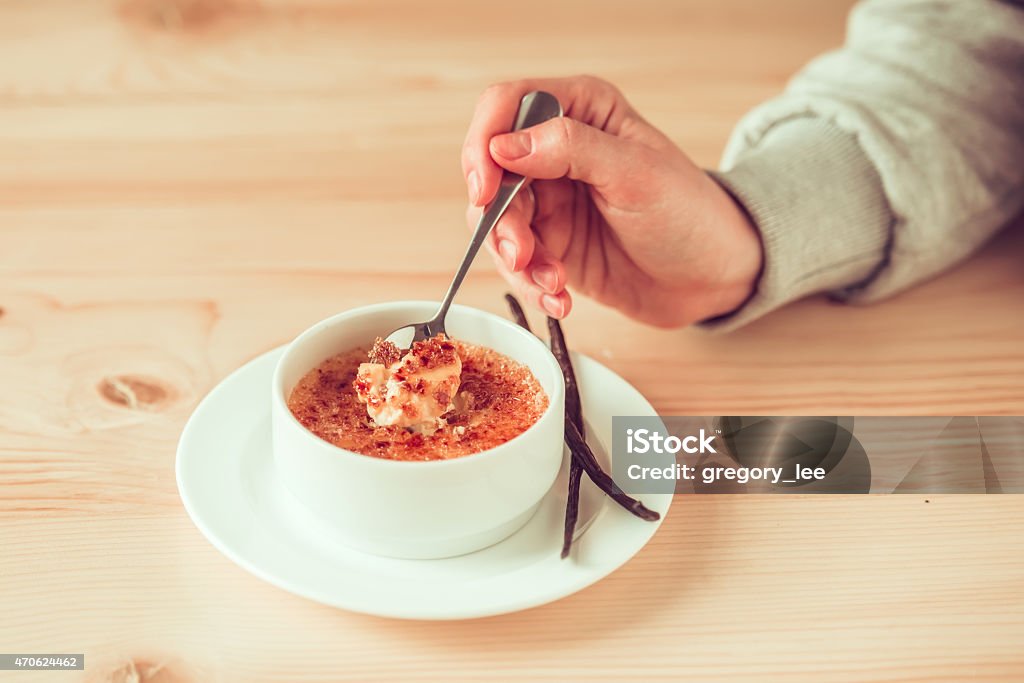 Creme brulee Creme brulee with bourbon vanilla sticks and hand with spoon. Toned picture 2015 Stock Photo