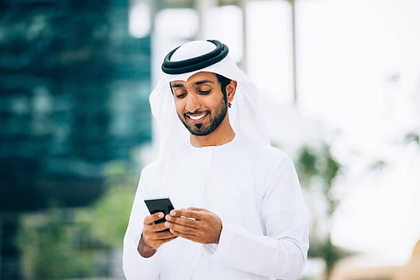 émirati en utilisant un téléphone mobile intelligent - émirats arabes unis photos et images de collection