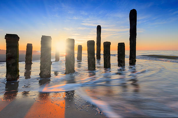 waves breaking on a wooden breakwater on the beach of Burgh-Haamstede, a small village along the Dutch coast. due to a long exposure the sea is blurred; Burgh-Haamstede, Netherlands