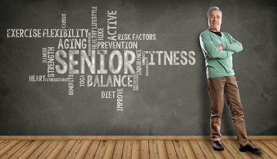Senior Man, Fitness, Healthy Lifestyle Word Cloud on Blackboard background. Happy Man standing on wooden floor, against a Blackboard background